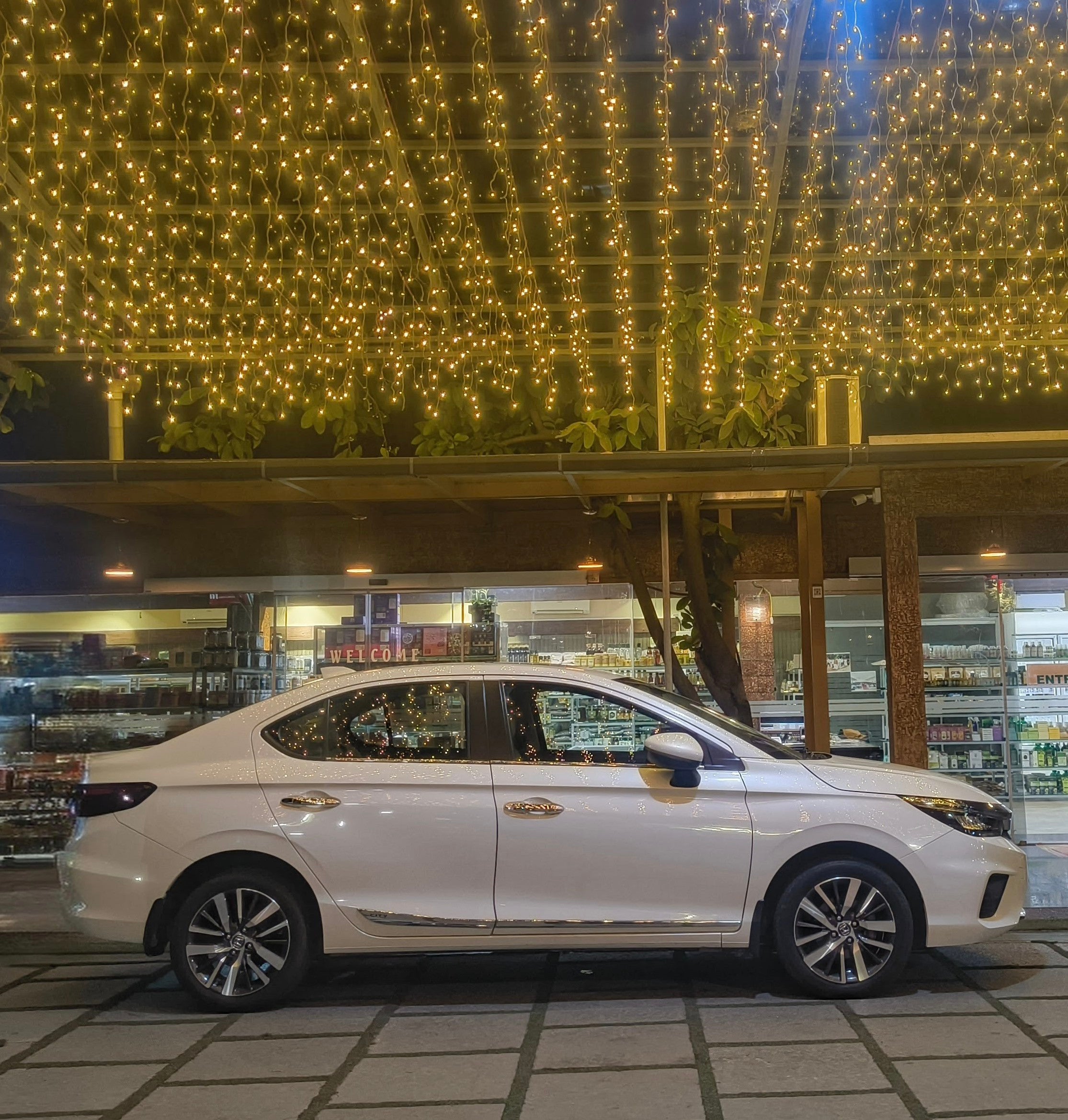 side view of a Honda City parked at night under string lights