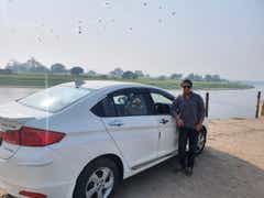rear-side view of a Honda City parked by a riverside