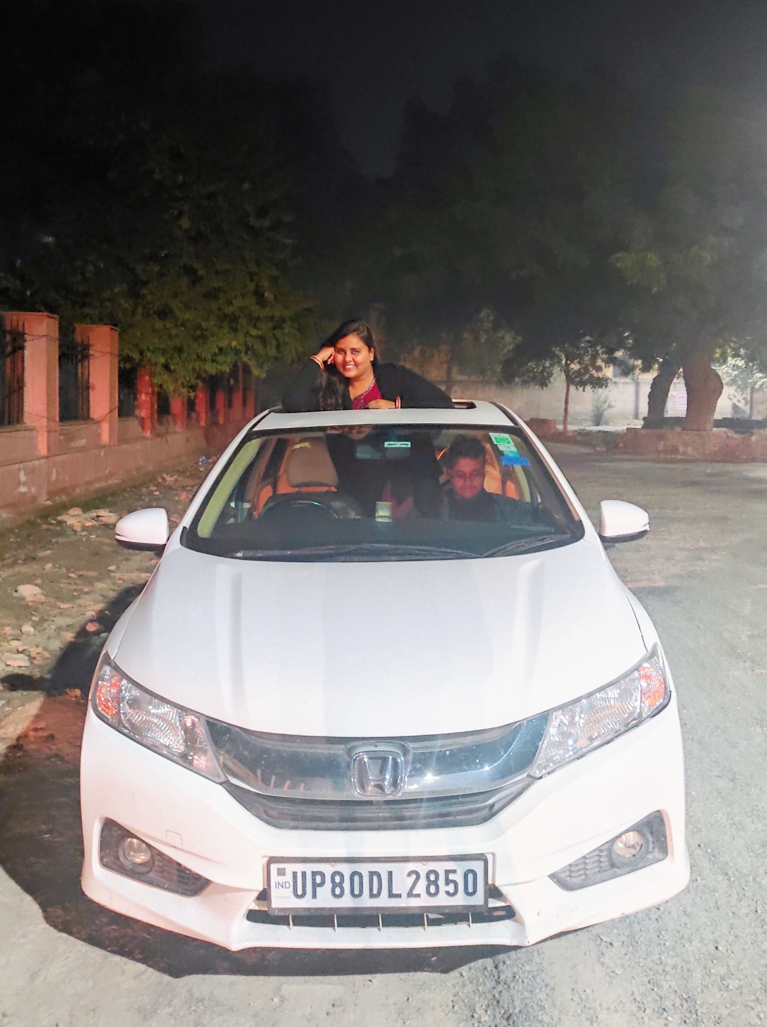 Front view of a Honda City with a person standing through sunroof