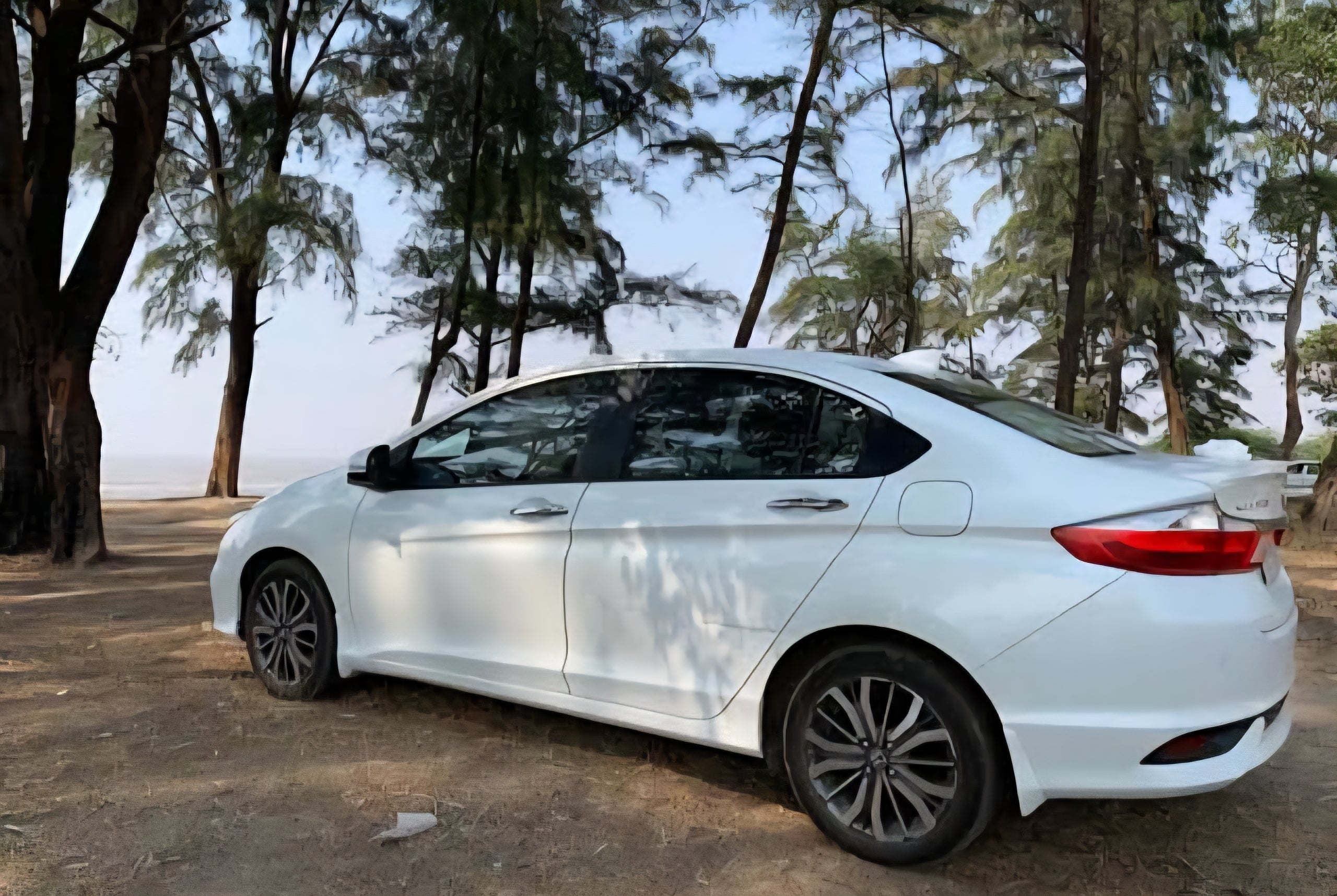 side view of a Honda City parked outdoors near trees