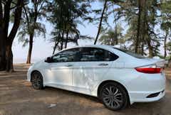 side view of a Honda City parked outdoors near trees