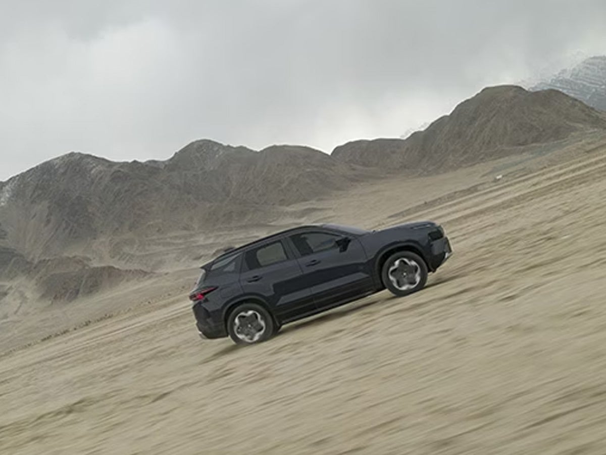 side view of a Tata Harrier EV driving in a desert landscape