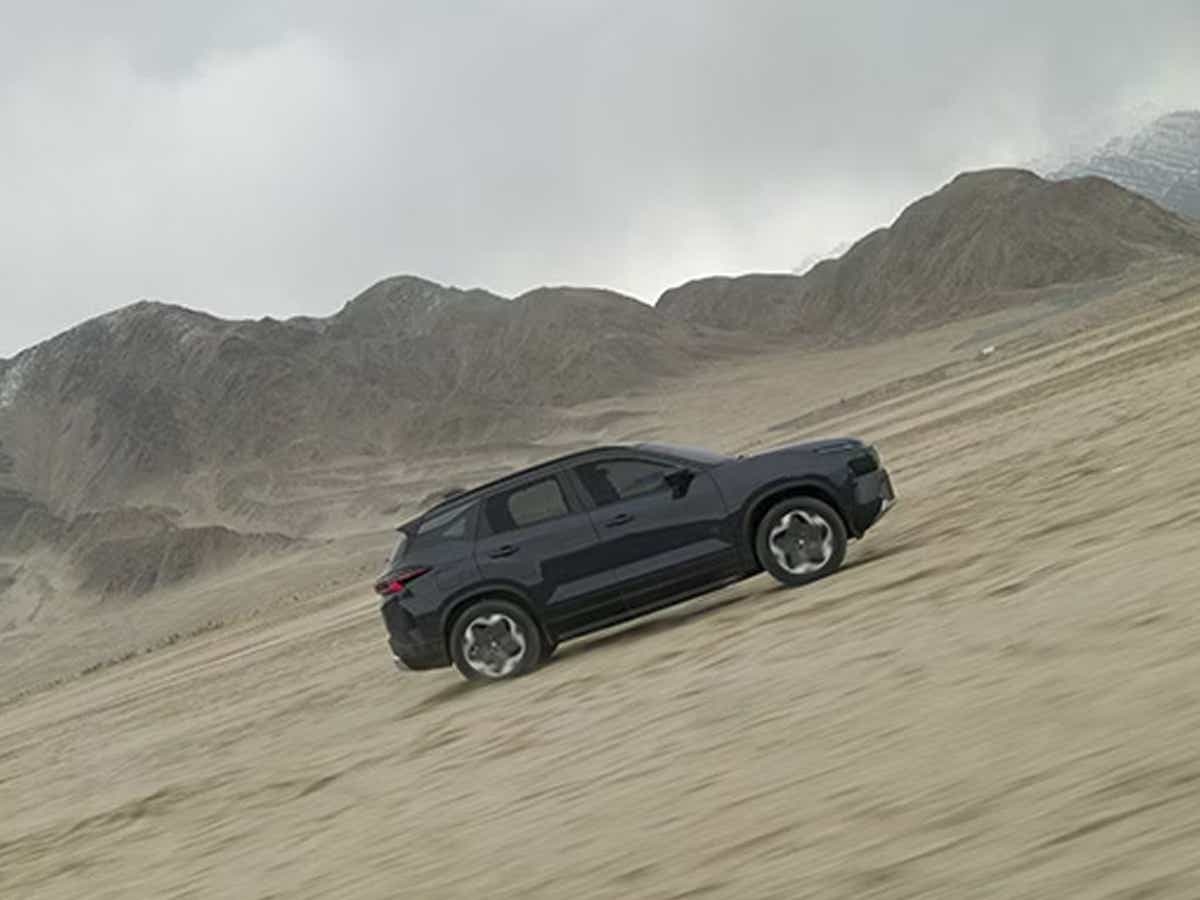 side view of a Tata Harrier EV driving in a desert landscape