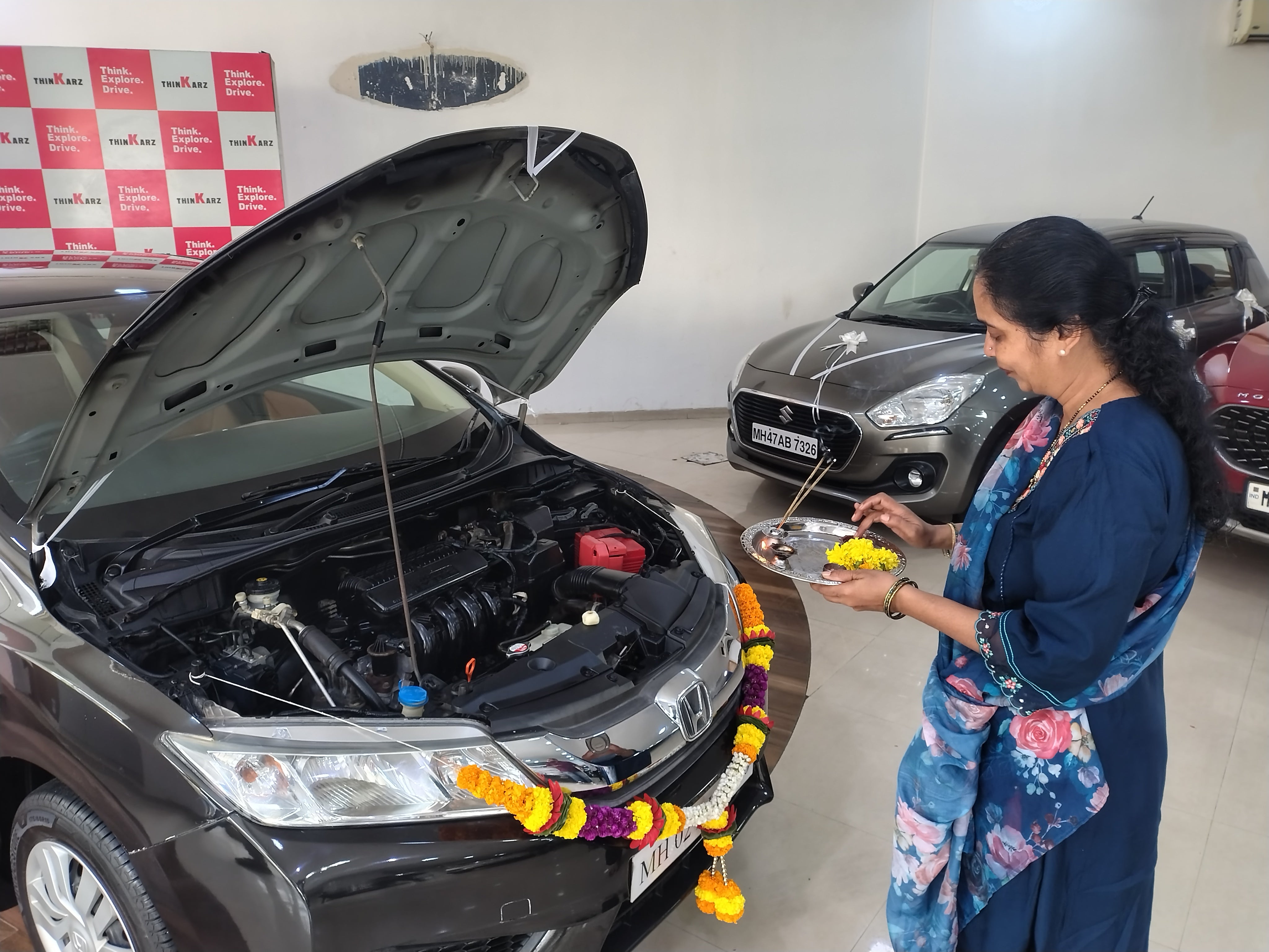 Front view of a Honda City with hood open during ritual in showroom