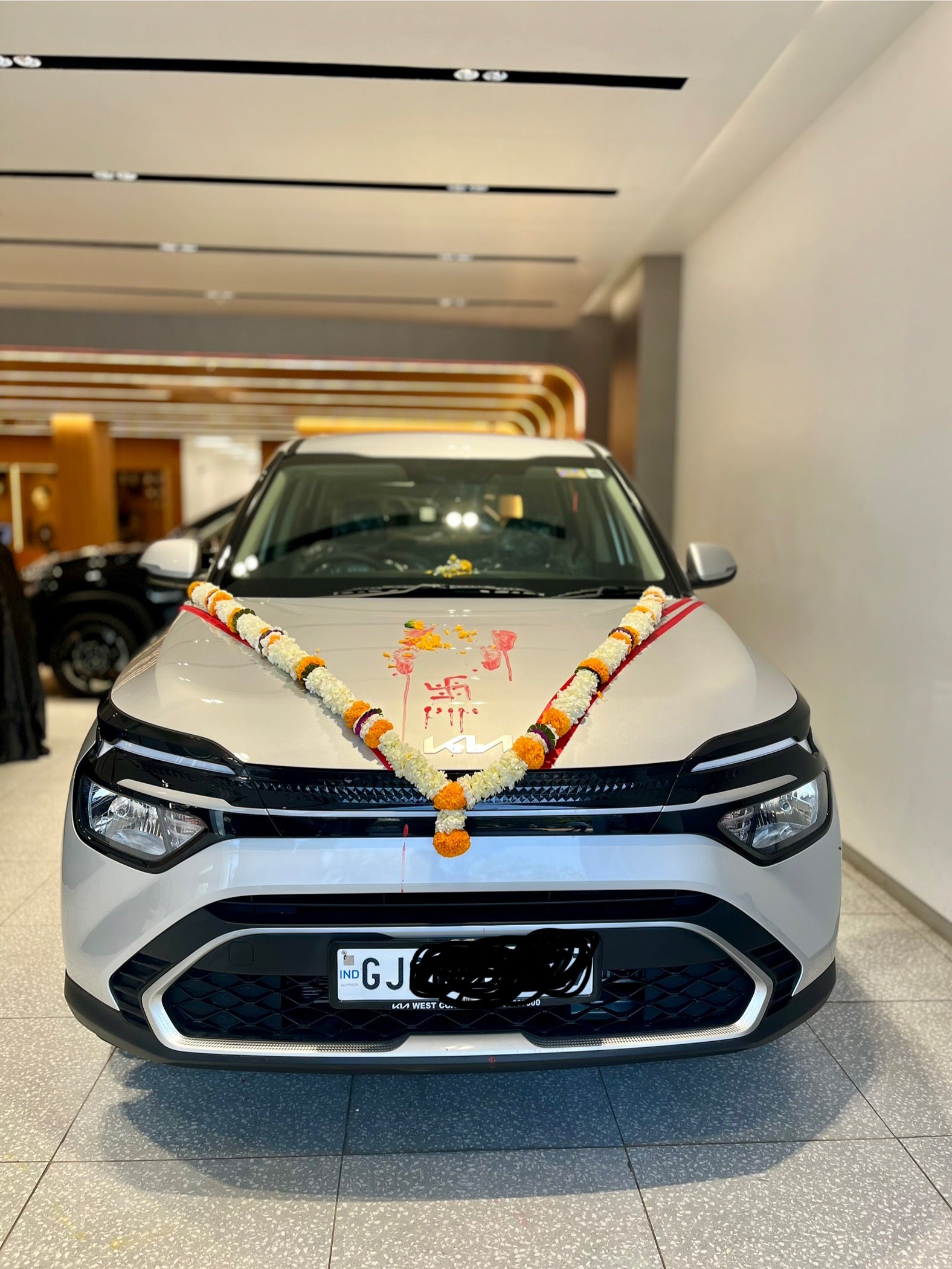 Front view of a Kia Carens decorated with garlands in a showroom