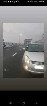 Front view of a Maruti Suzuki Dzire on a city bridge