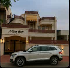 Side view of a moon white Skoda Kodiaq in front of a house