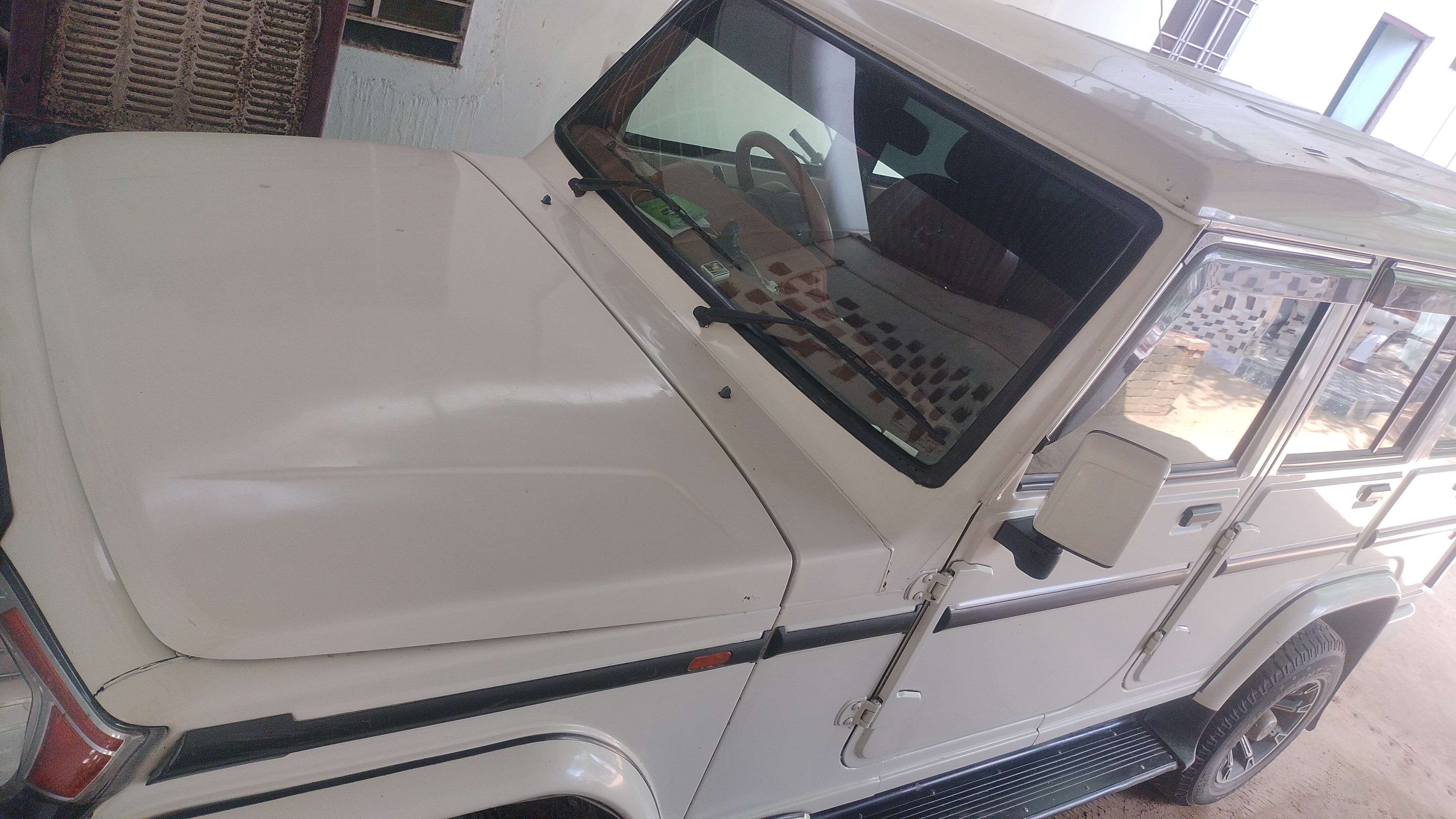 Front and side view of a diamond white Mahindra Bolero