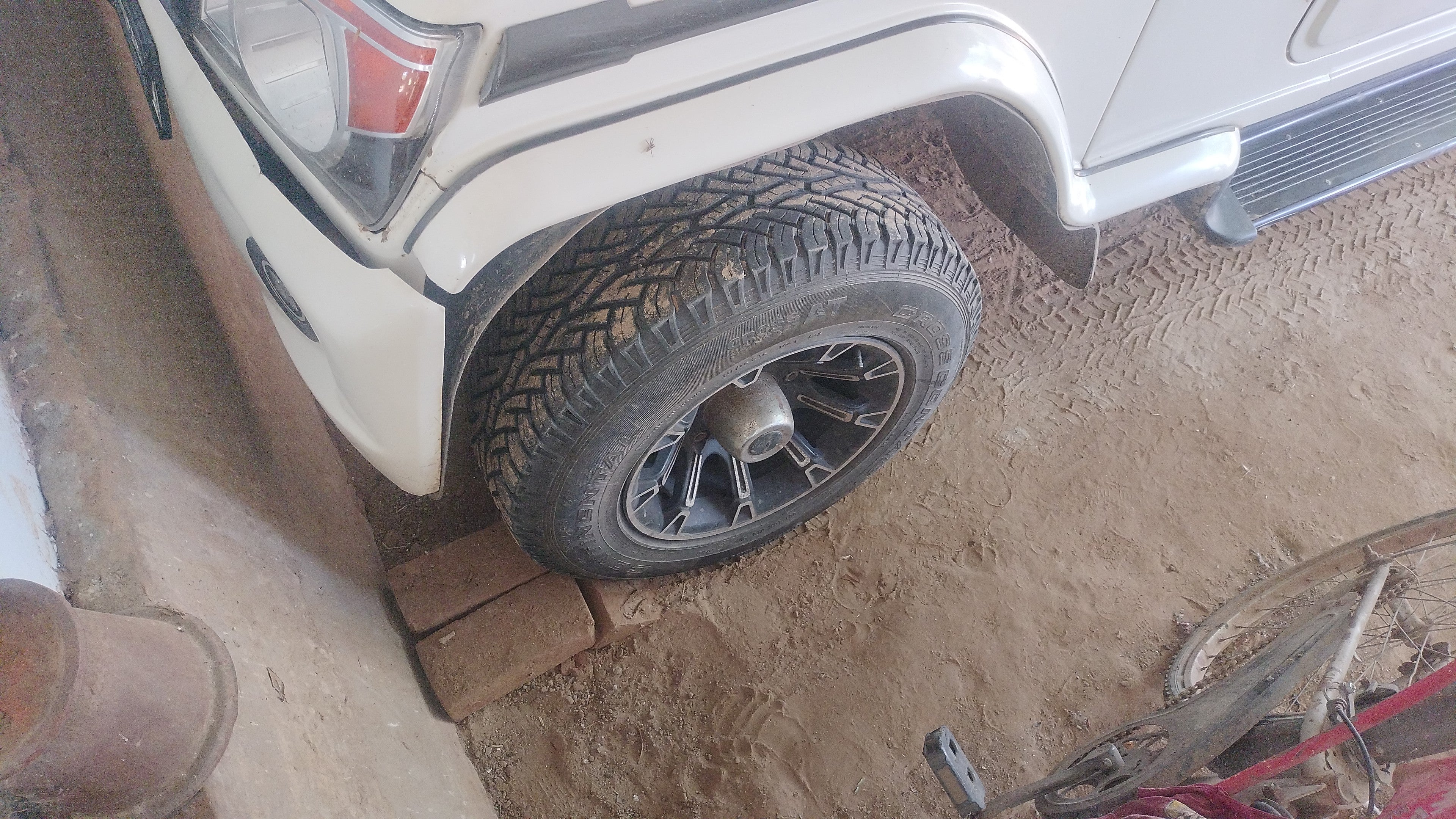 Front left tyre and fender of a diamond white Mahindra Bolero