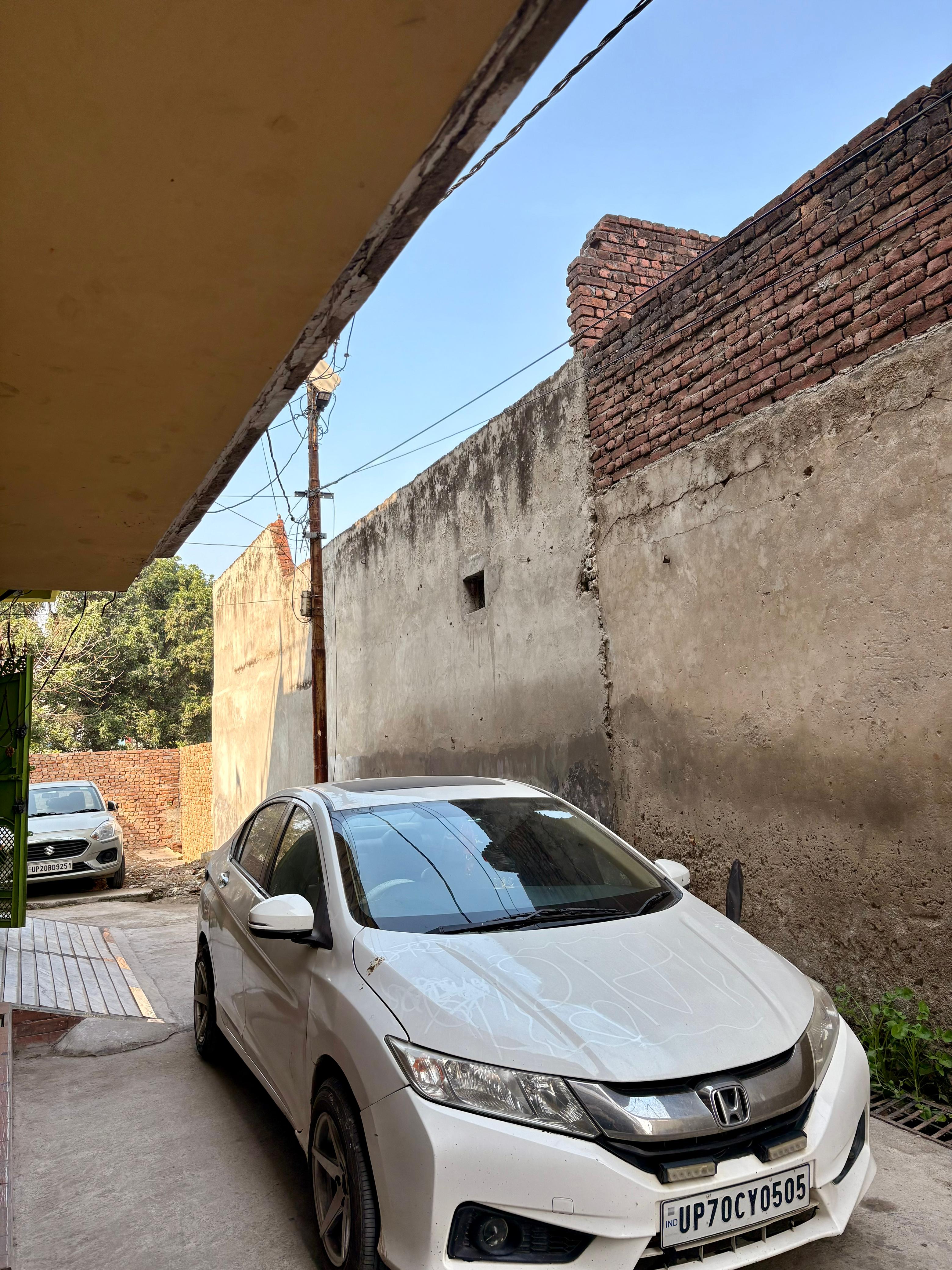 front three-quarter view of a Honda City parked beside a wall