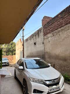 front three-quarter view of a Honda City parked beside a wall