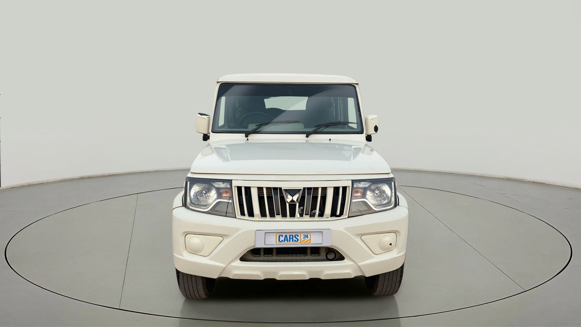 Front view of a diamond white Mahindra Bolero