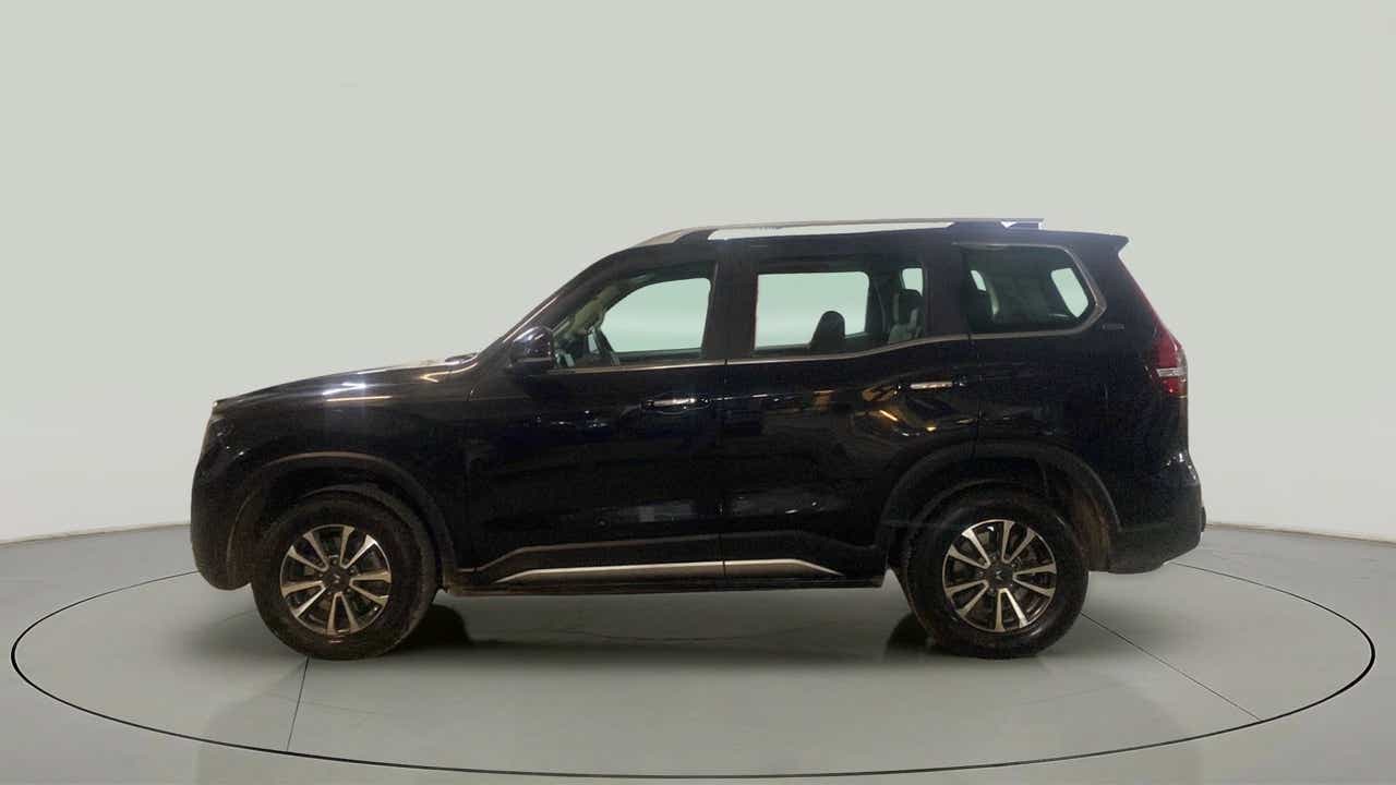 Side view of a deep forest Mahindra Scorpio-N