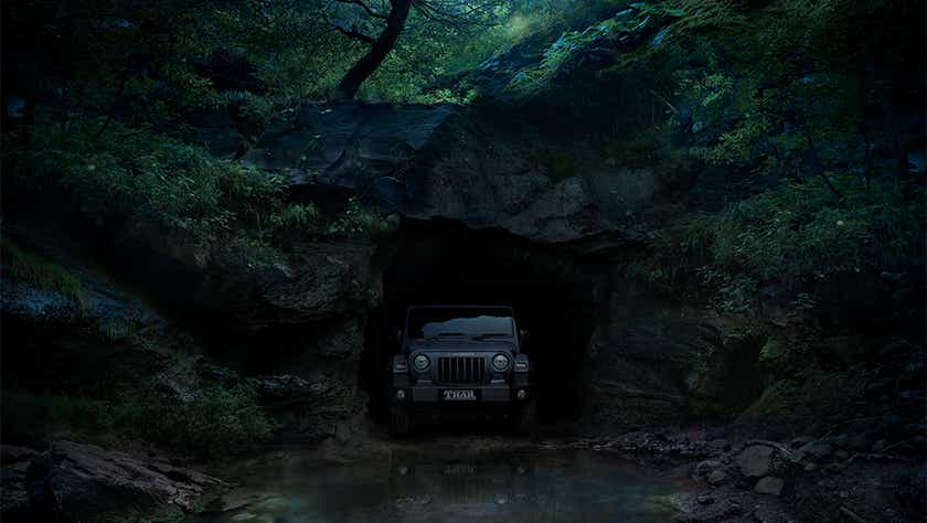 Front view of a Mahindra Thar emerging from a cave