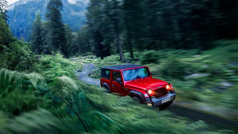 Front three-quarter view of a tango-red Mahindra Thar