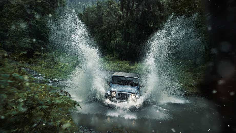 Front view of a galaxy grey Mahindra Thar splashing through water