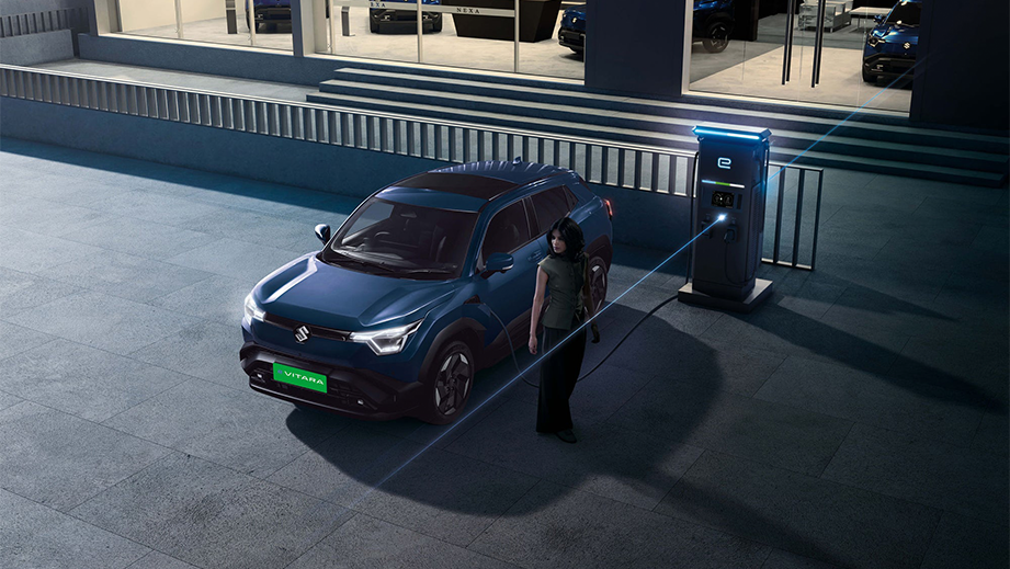 Front three-quarter view of a Nexa Blue Maruti Suzuki e Vitara charging at a station