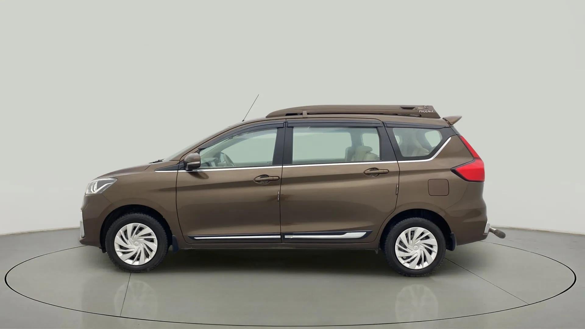 Left side view of a Pearl Metallic Dignity Brown Maruti Suzuki Ertiga