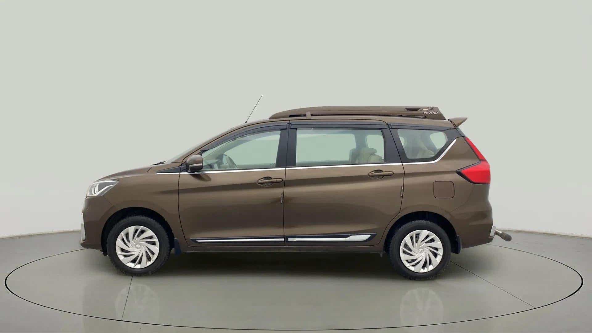 Left side view of a Pearl Metallic Dignity Brown Maruti Suzuki Ertiga