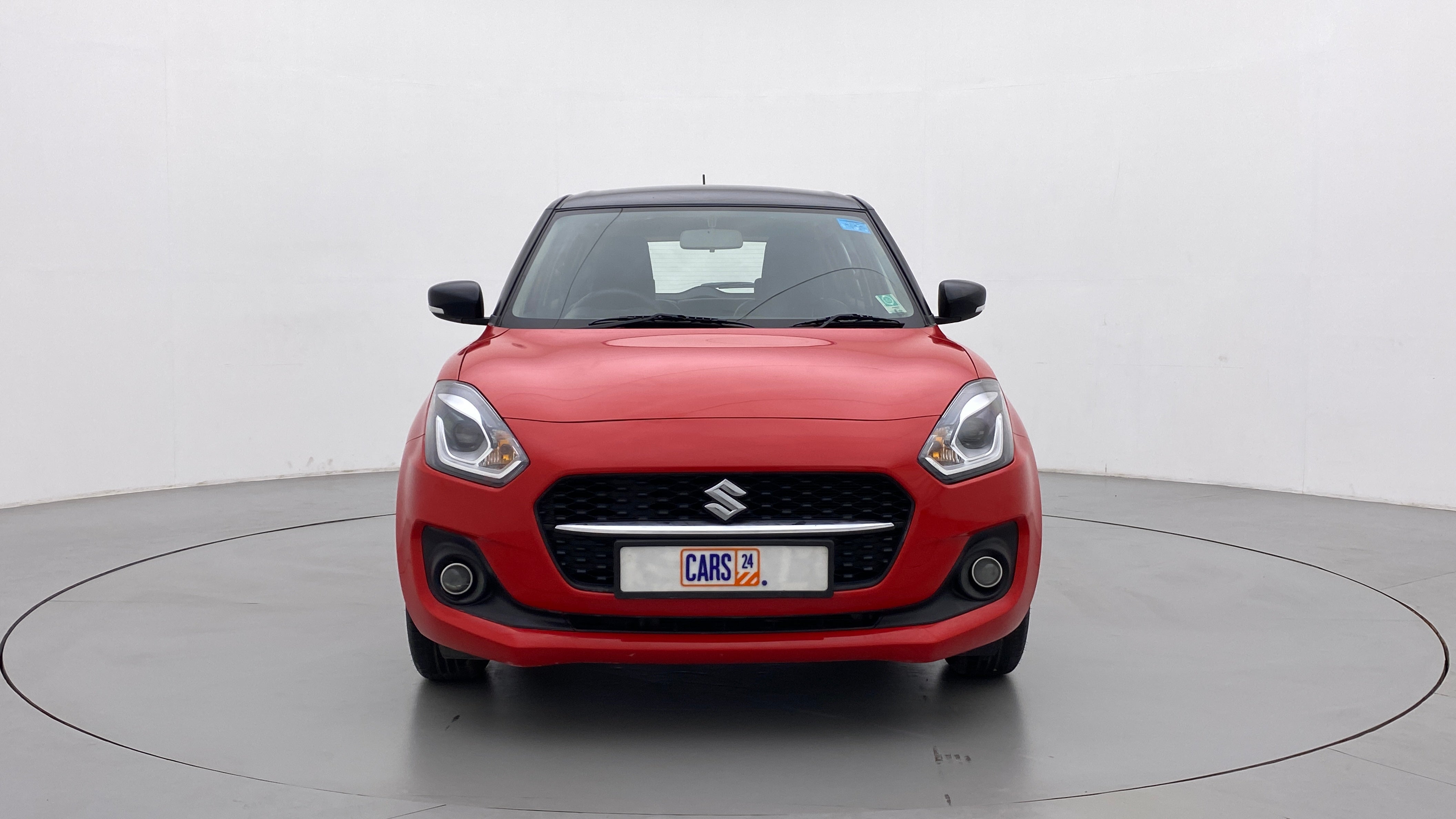 Front view of a solid fire red with pearl midnight black roof Maruti Suzuki Swift 2021 - 2023