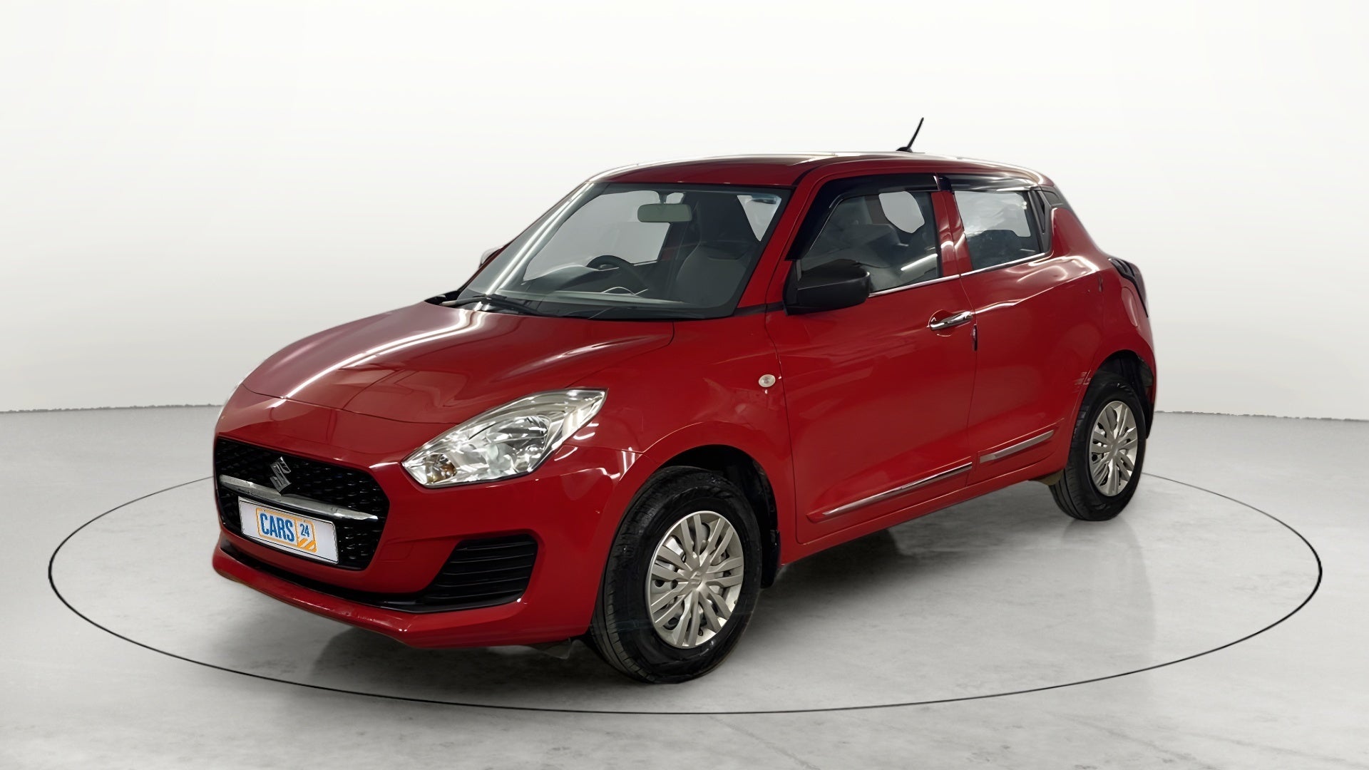 Front three-quarter view of a solid fire red with pearl midnight black roof Maruti Suzuki Swift 2021 - 2023