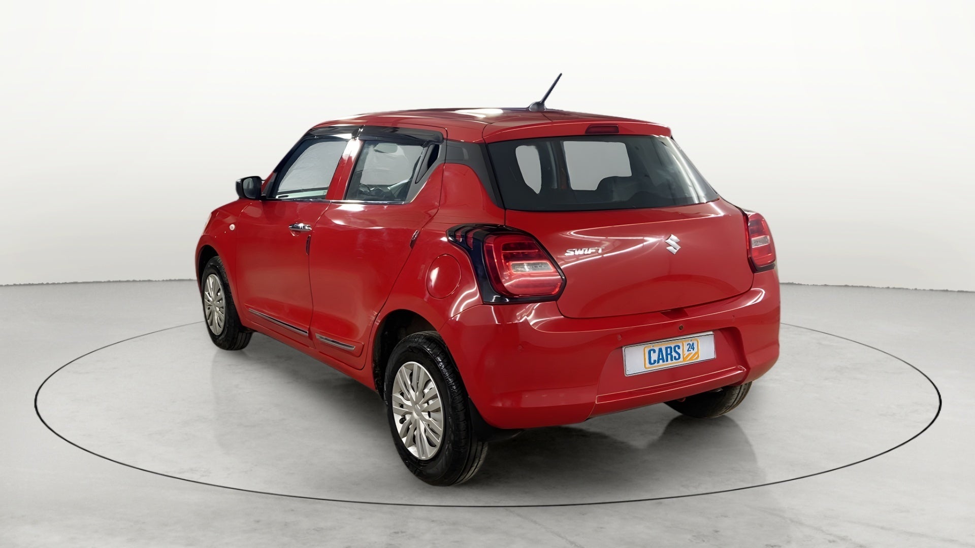Rear three-quarter view of a solid fire red with pearl midnight black roof Maruti Suzuki Swift 2021 - 2023