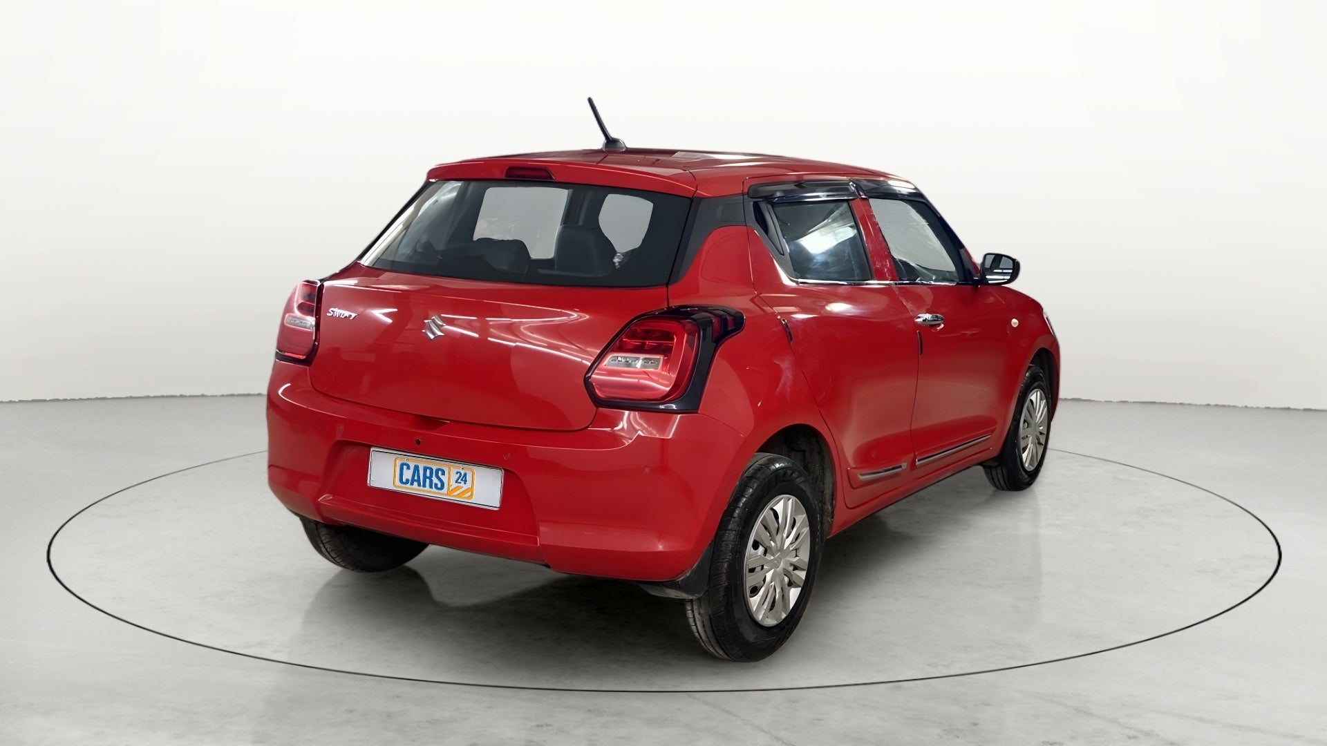 Rear three-quarter view of a solid fire red with pearl midnight black roof maruti suzuki swift 2021 - 2023