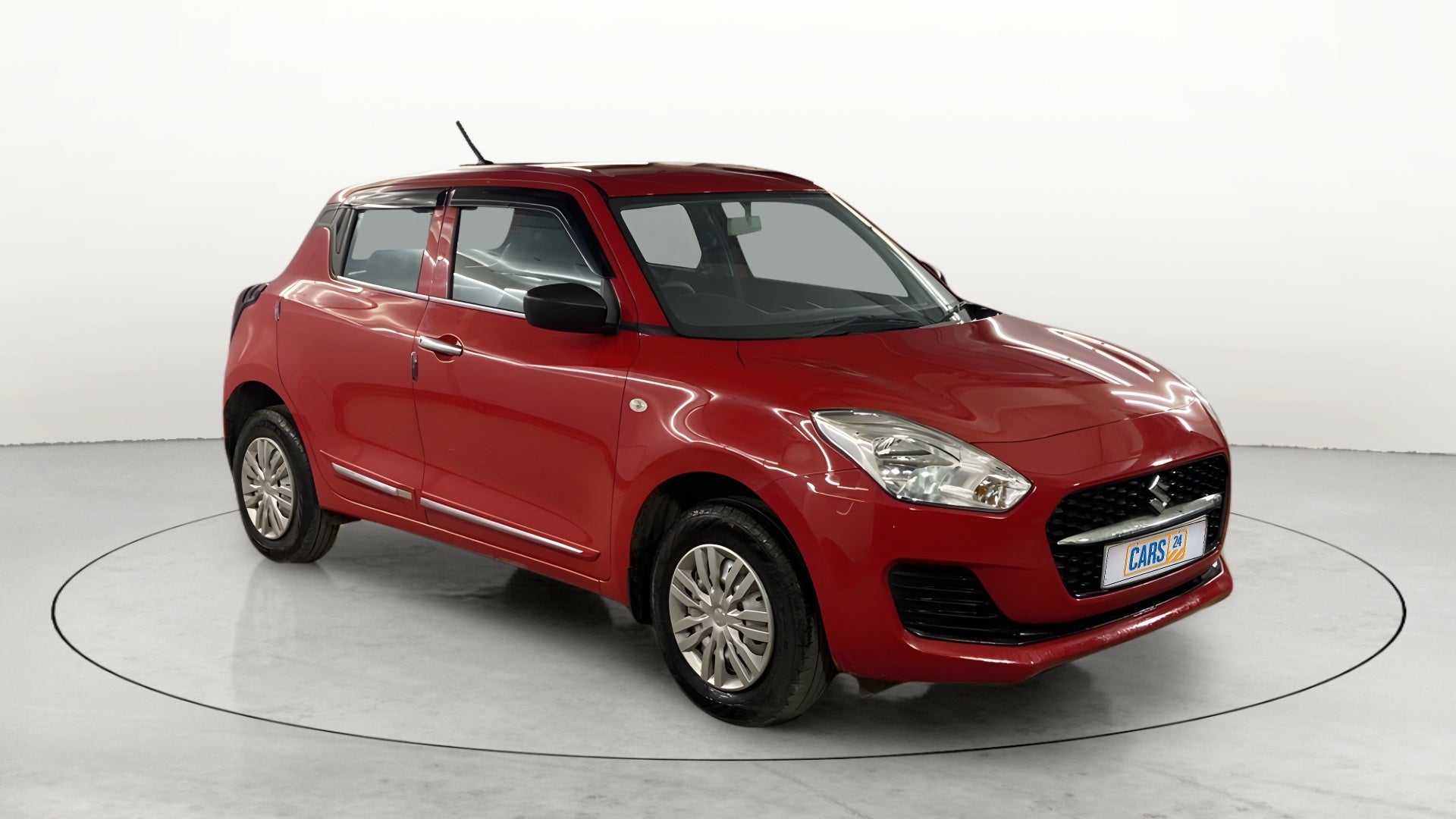 Front three-quarter view of a solid fire red Maruti Suzuki Swift 2021 - 2023