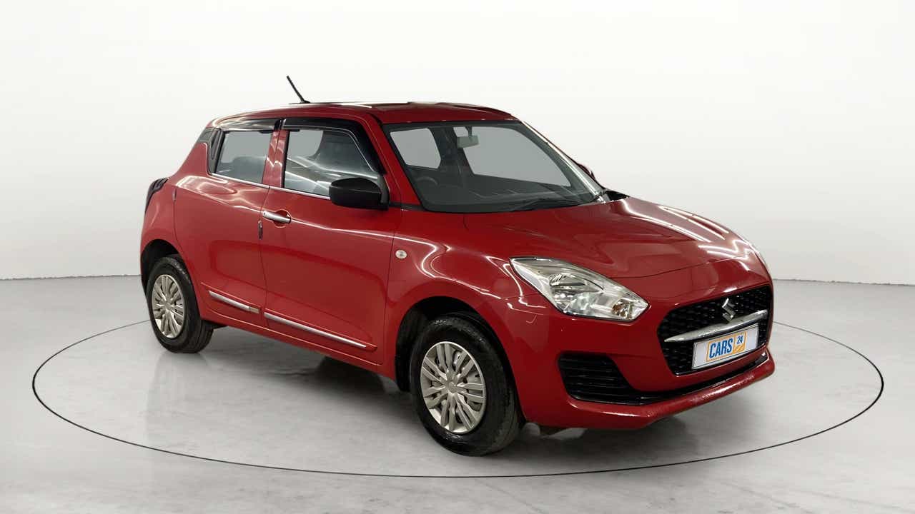 Front three-quarter view of a solid fire red Maruti Suzuki Swift 2021 - 2023