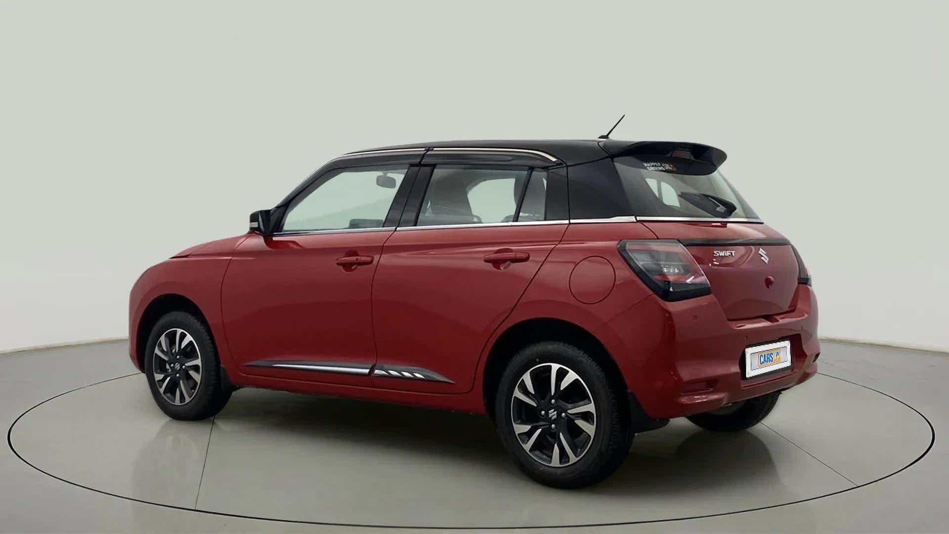 Rear three-quarter of a sizzling red with midnight black Maruti Suzuki Swift