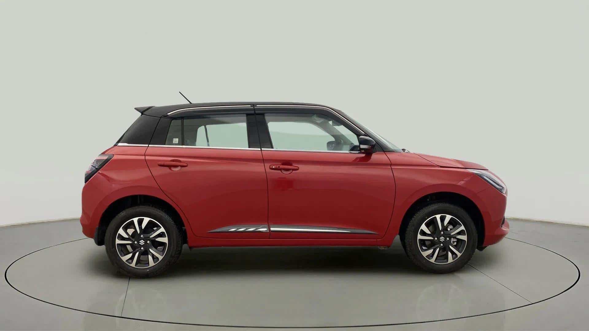 Side view of a sizzling red with midnight black Maruti Suzuki Swift