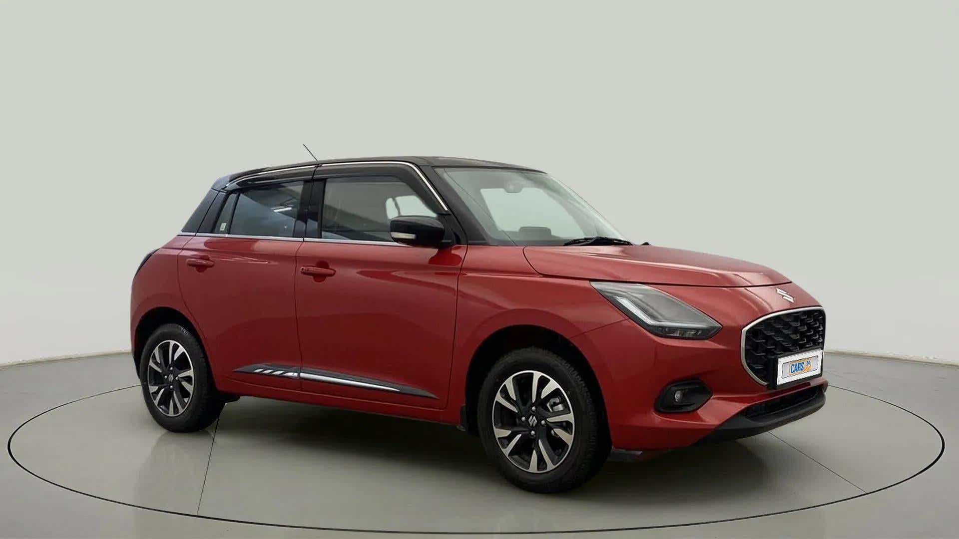 Front three-quarter view of a sizzling red with midnight black Maruti Suzuki Swift