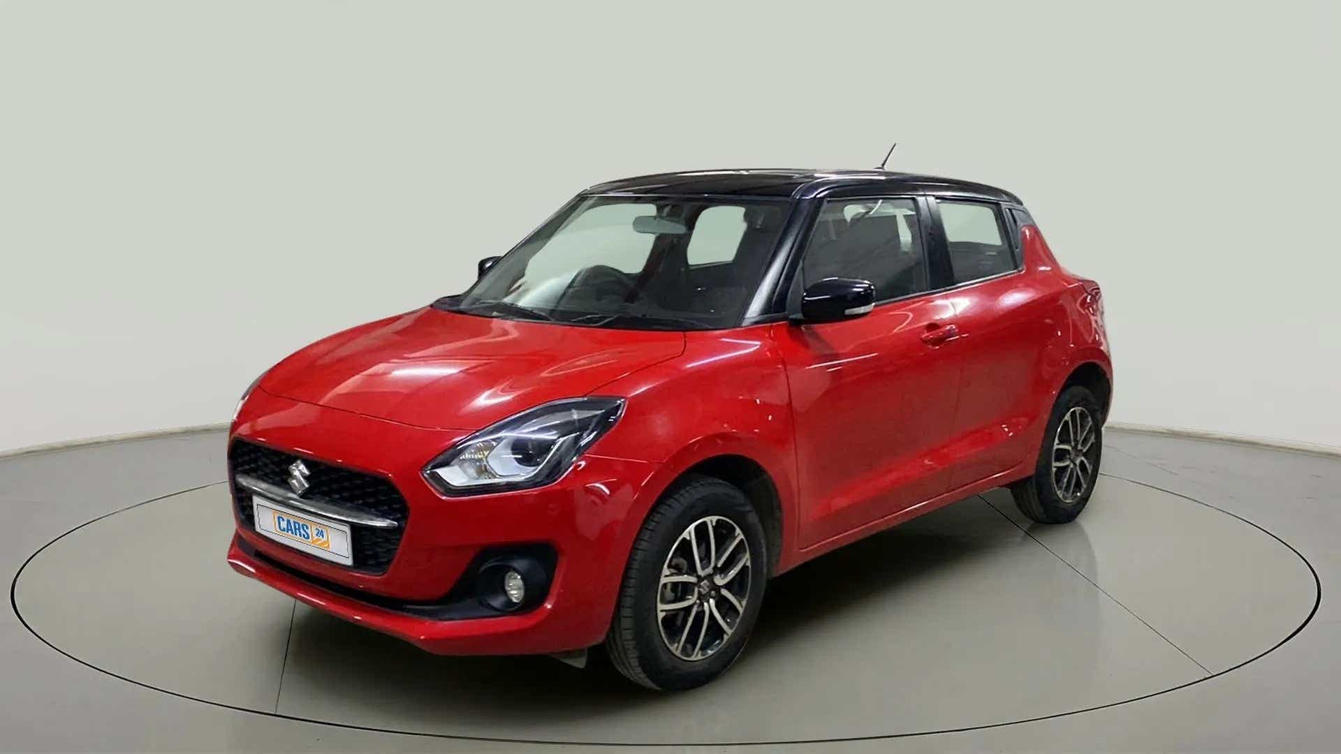 Front three-quarter view of a solid fire red with pearl midnight black roof Maruti Suzuki Swift 2021 - 2023