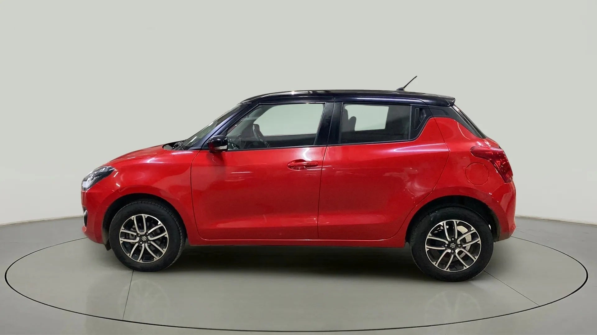 Side view of a solid fire red with pearl midnight black roof Maruti Suzuki Swift 2021 - 2023