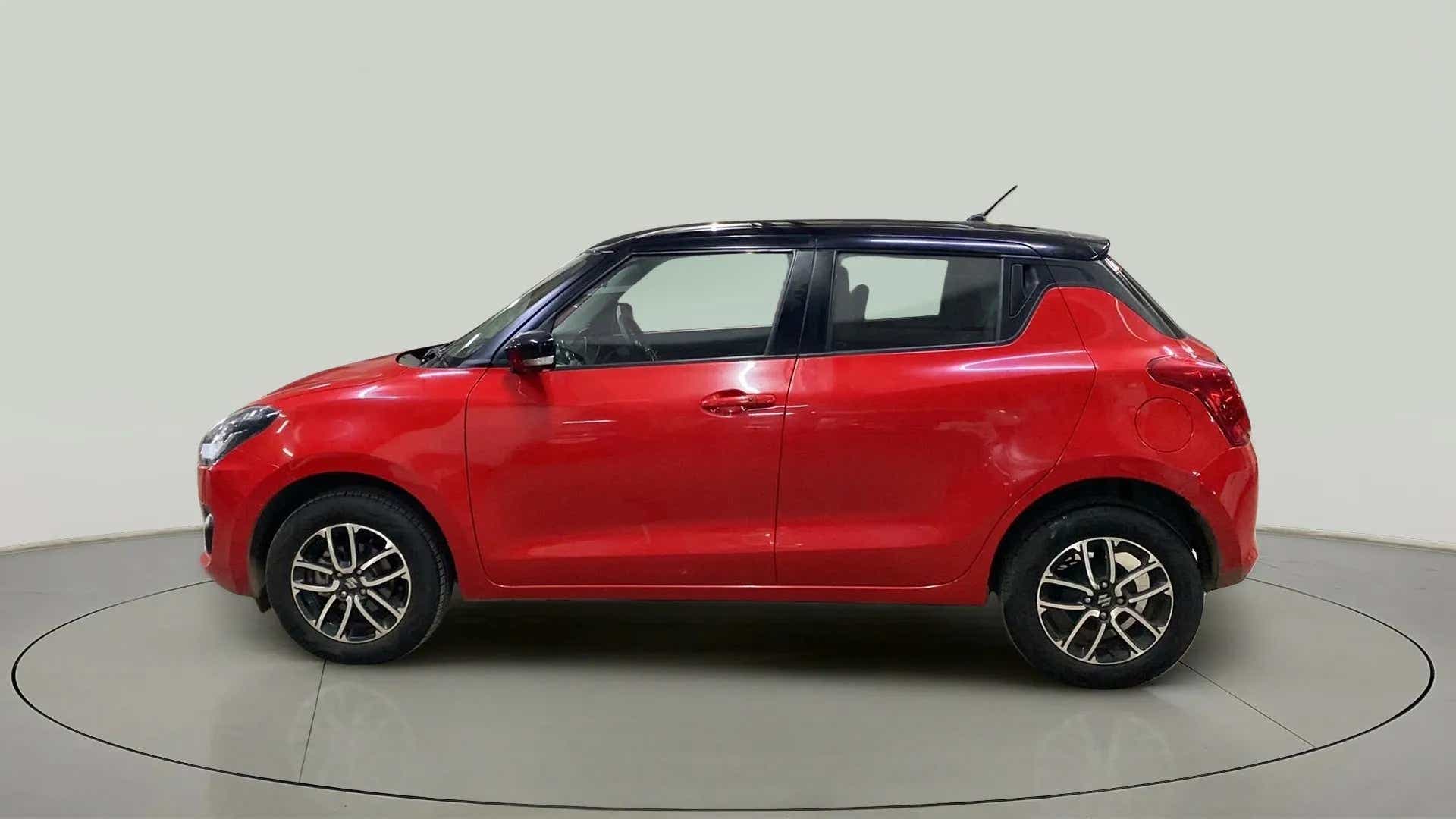 Side view of a solid fire red with pearl midnight black roof Maruti Suzuki Swift 2021 - 2023