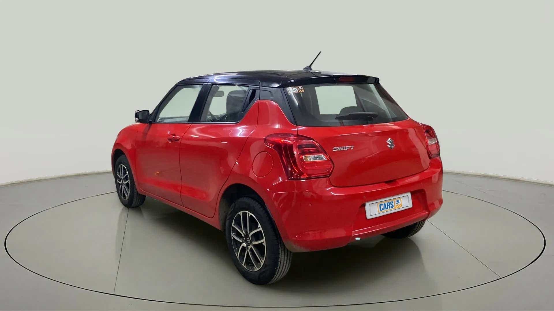 Rear three-quarter view of a solid fire red with pearl midnight black roof Maruti Suzuki Swift 2021 - 2023