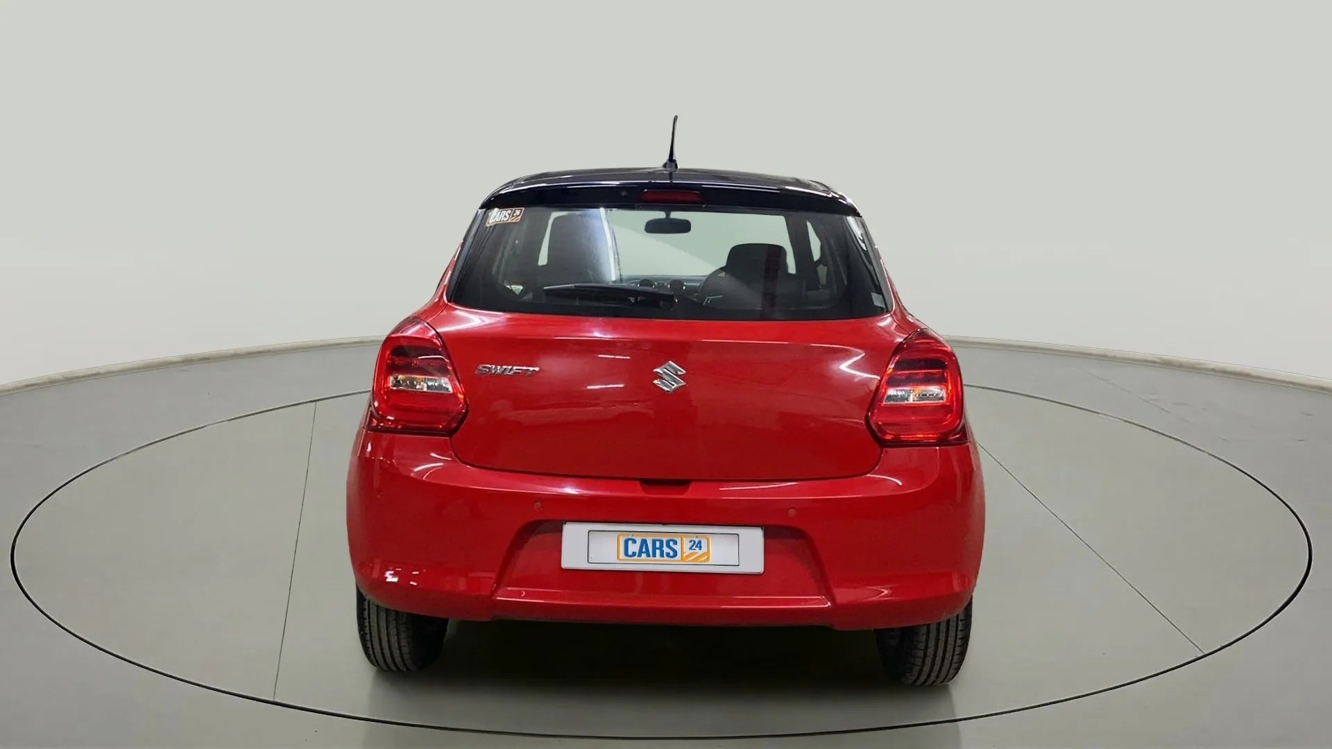 Rear view of a solid fire red with pearl midnight black roof Maruti Suzuki Swift 2021 - 2023