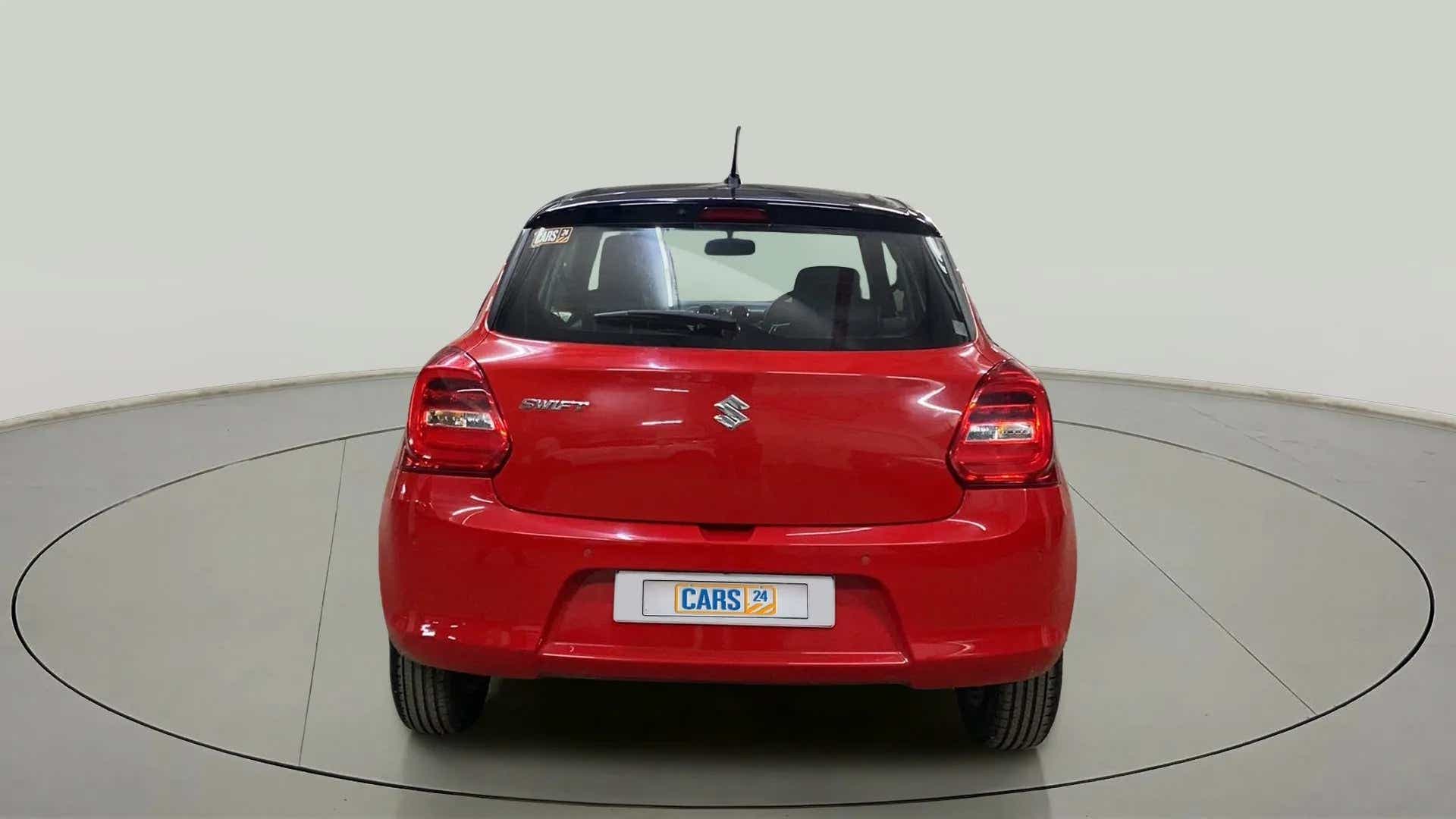 Rear view of a solid fire red with pearl midnight black roof Maruti Suzuki Swift 2021 - 2023