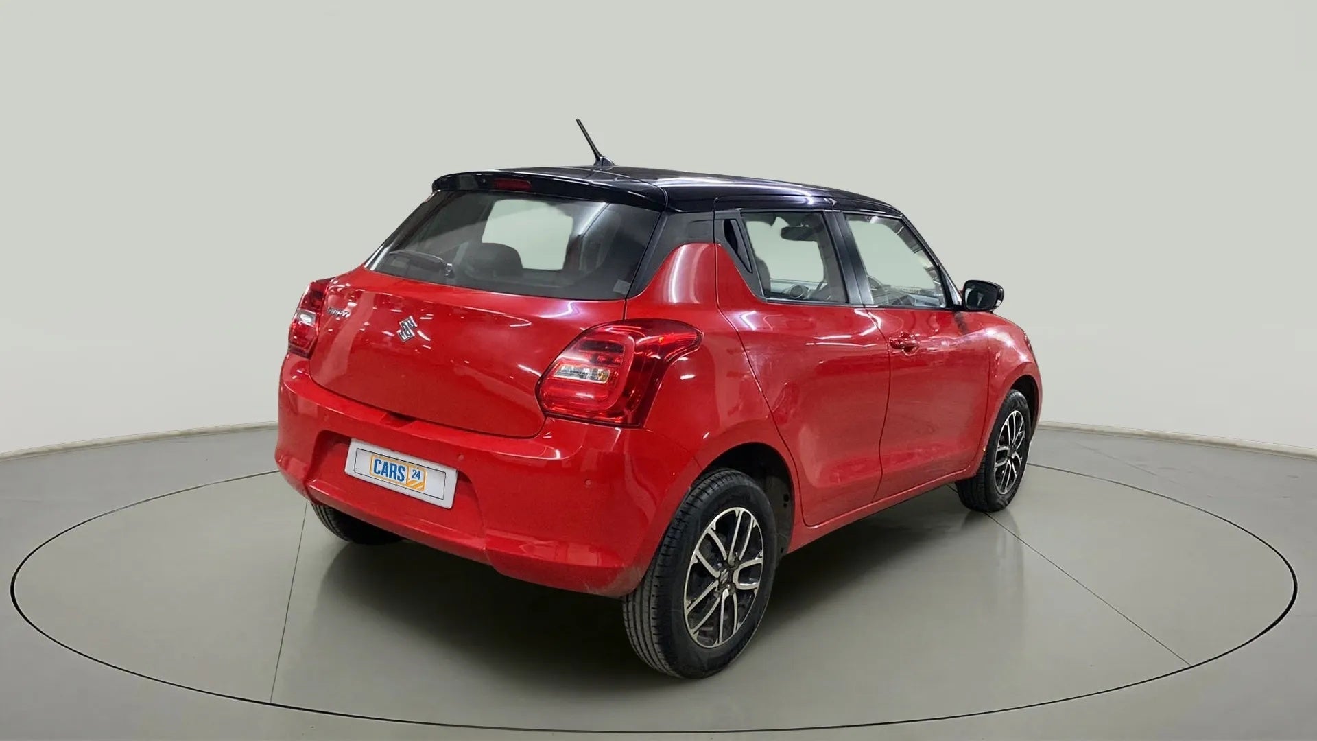 Rear three-quarter of a solid fire red with pearl midnight black roof Maruti Suzuki Swift 2021 - 2023