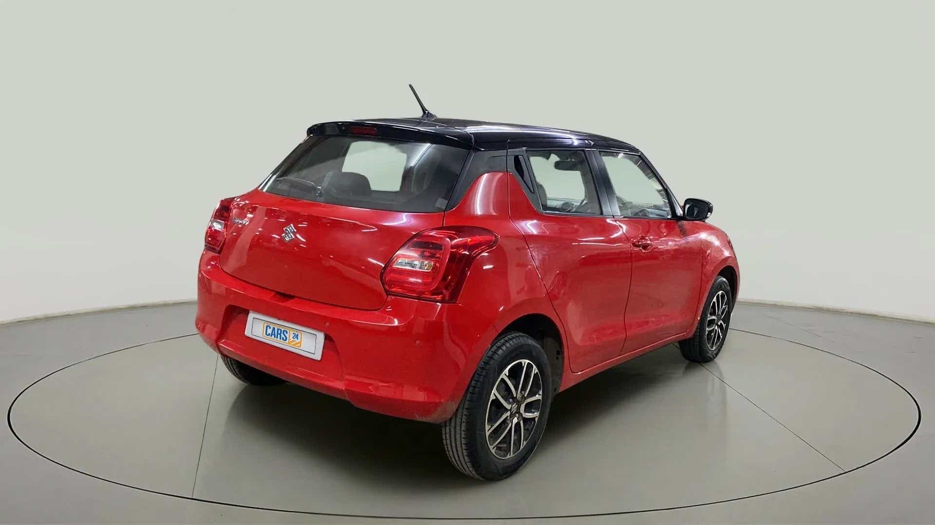 Rear three-quarter of a solid fire red with pearl midnight black roof Maruti Suzuki Swift 2021 - 2023
