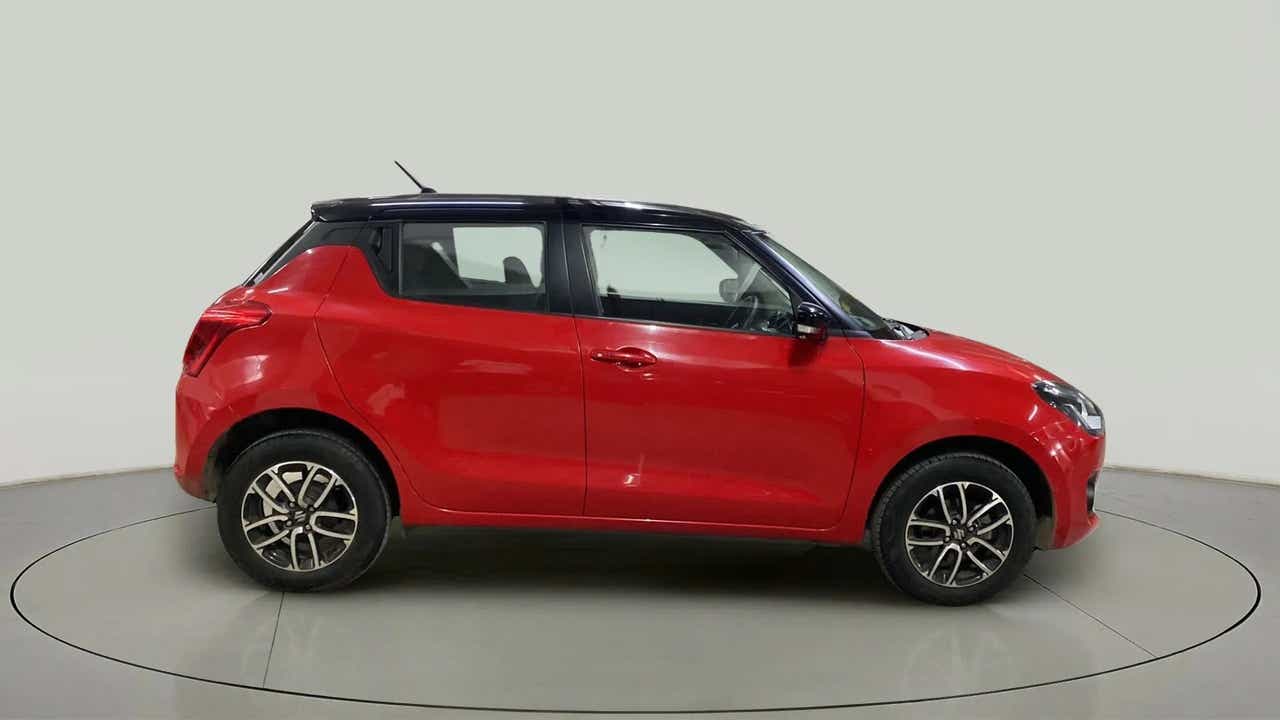 Side view of a solid fire red with pearl midnight black roof Maruti Suzuki Swift 2021 - 2023