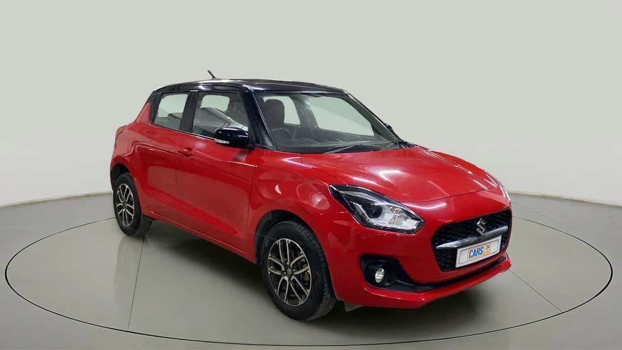 Front three-quarter view of a solid fire red with pearl midnight black roof Maruti Suzuki Swift 2021 - 2023