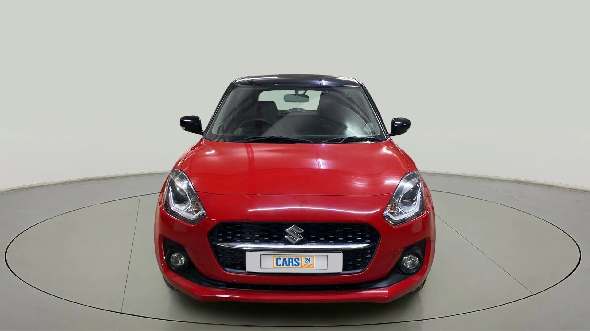 Front view of a solid fire red with pearl midnight black roof Maruti Suzuki Swift 2021 - 2023