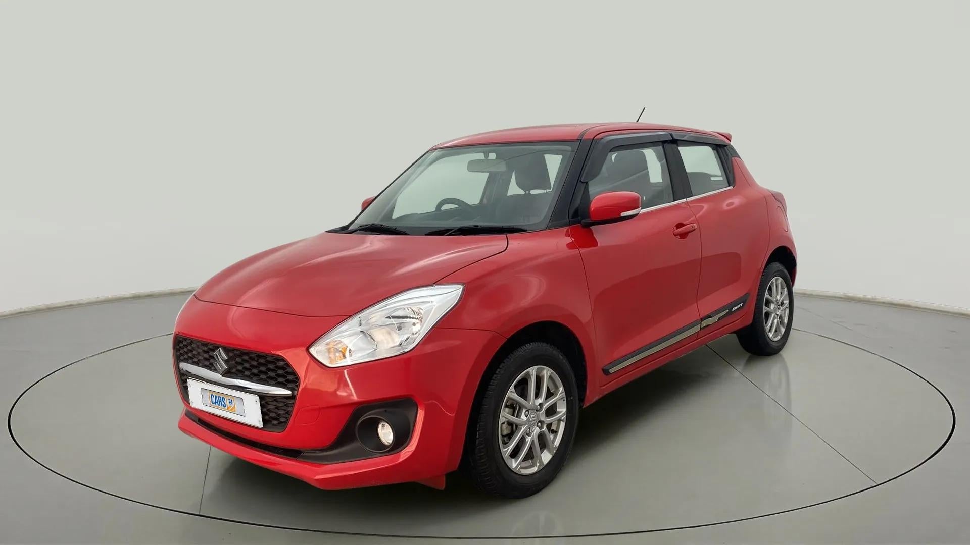 Front three-quarter view of a solid fire red with pearl midnight black roof Maruti Suzuki Swift 2021 - 2023