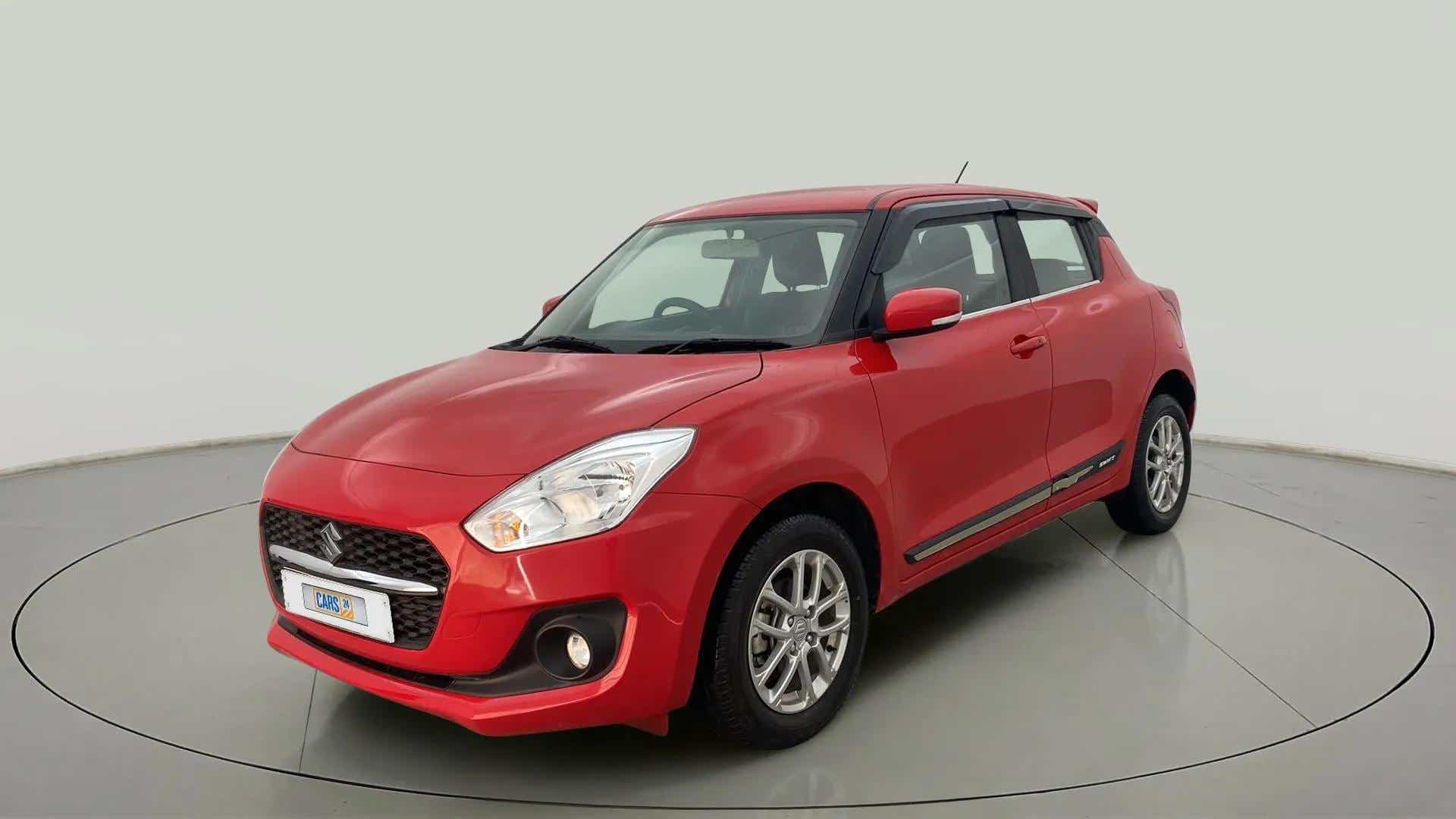 Front three-quarter view of a solid fire red with pearl midnight black roof Maruti Suzuki Swift 2021 - 2023