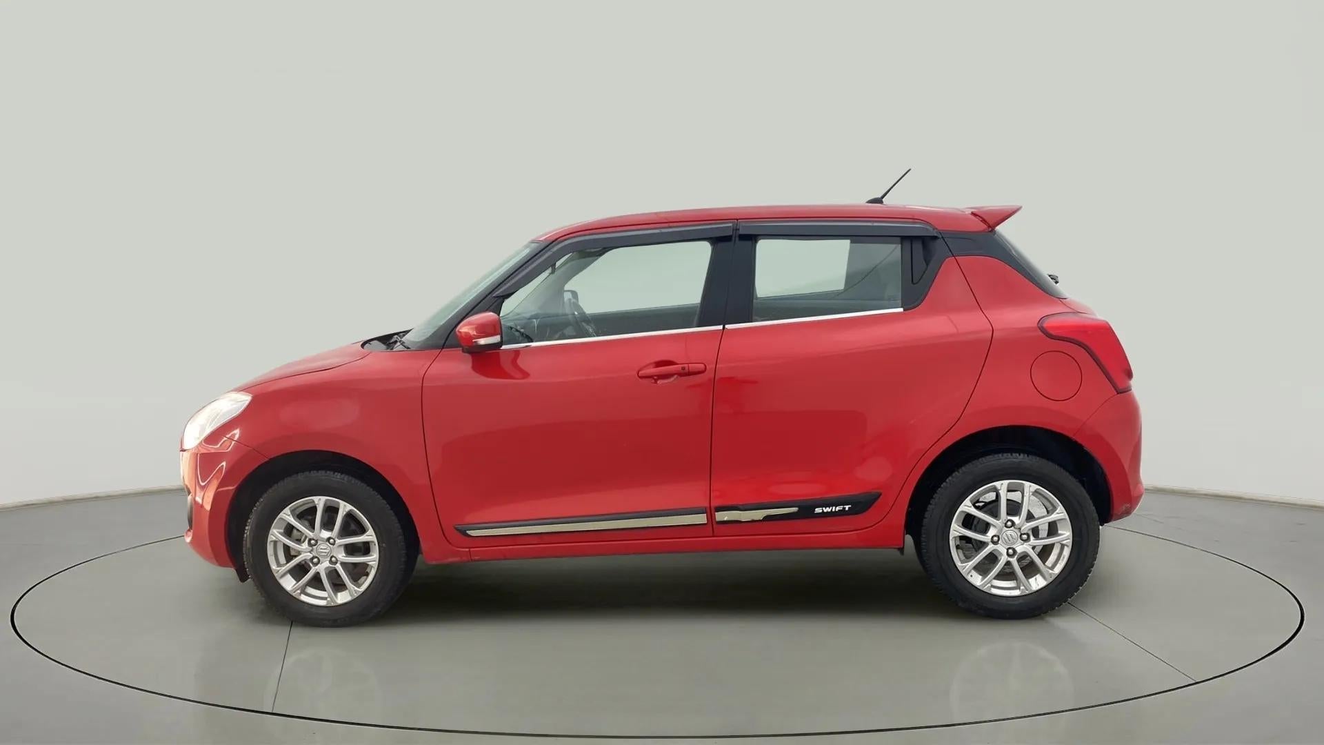 Side view of a solid fire red with pearl midnight black roof Maruti Suzuki Swift 2021 - 2023