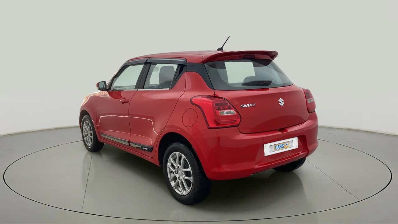 Rear three-quarter view of a solid fire red with pearl midnight black roof Maruti Suzuki Swift 2021 - 2023