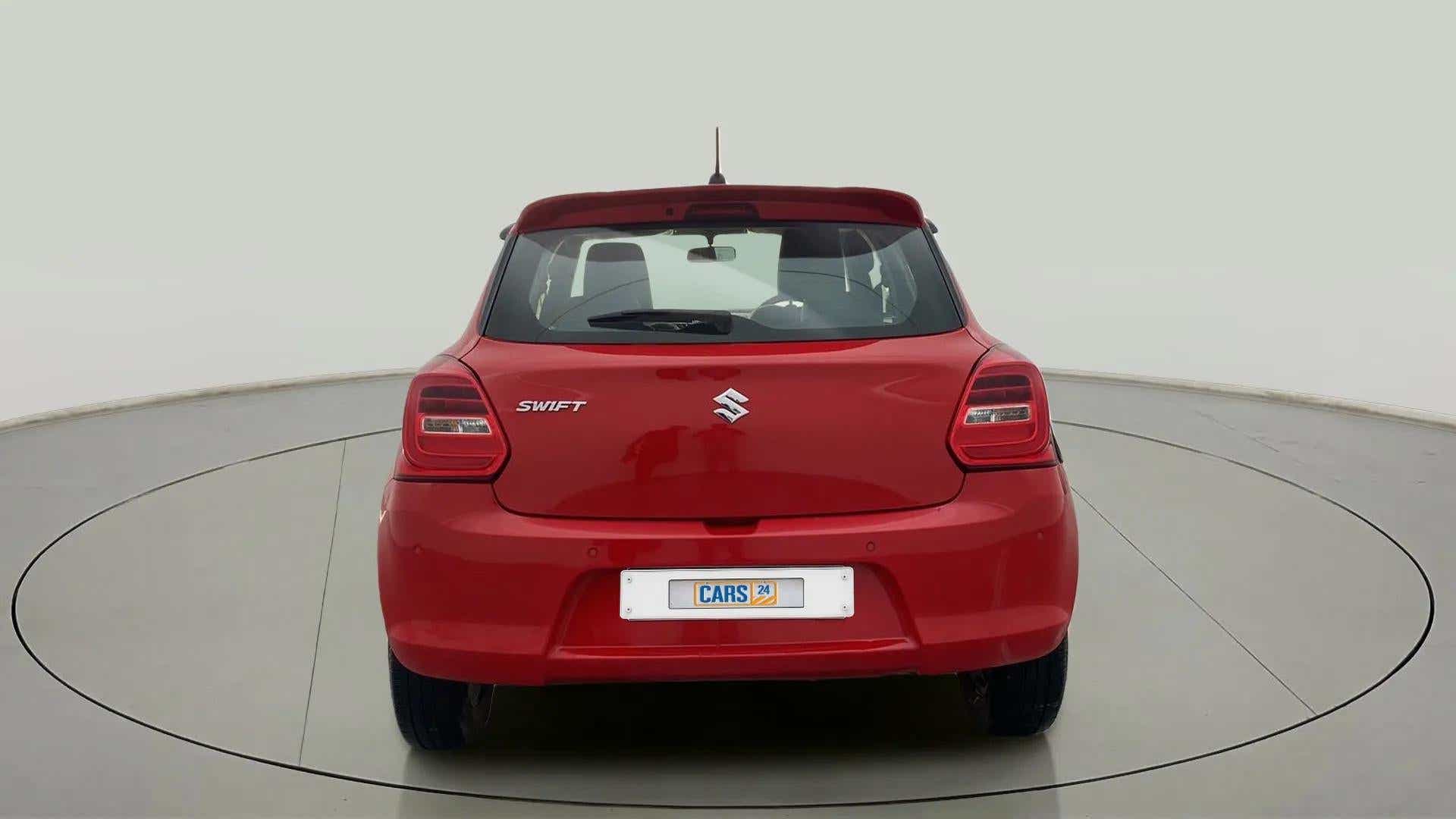 Rear view of a solid fire red maruti suzuki swift 2021 - 2023