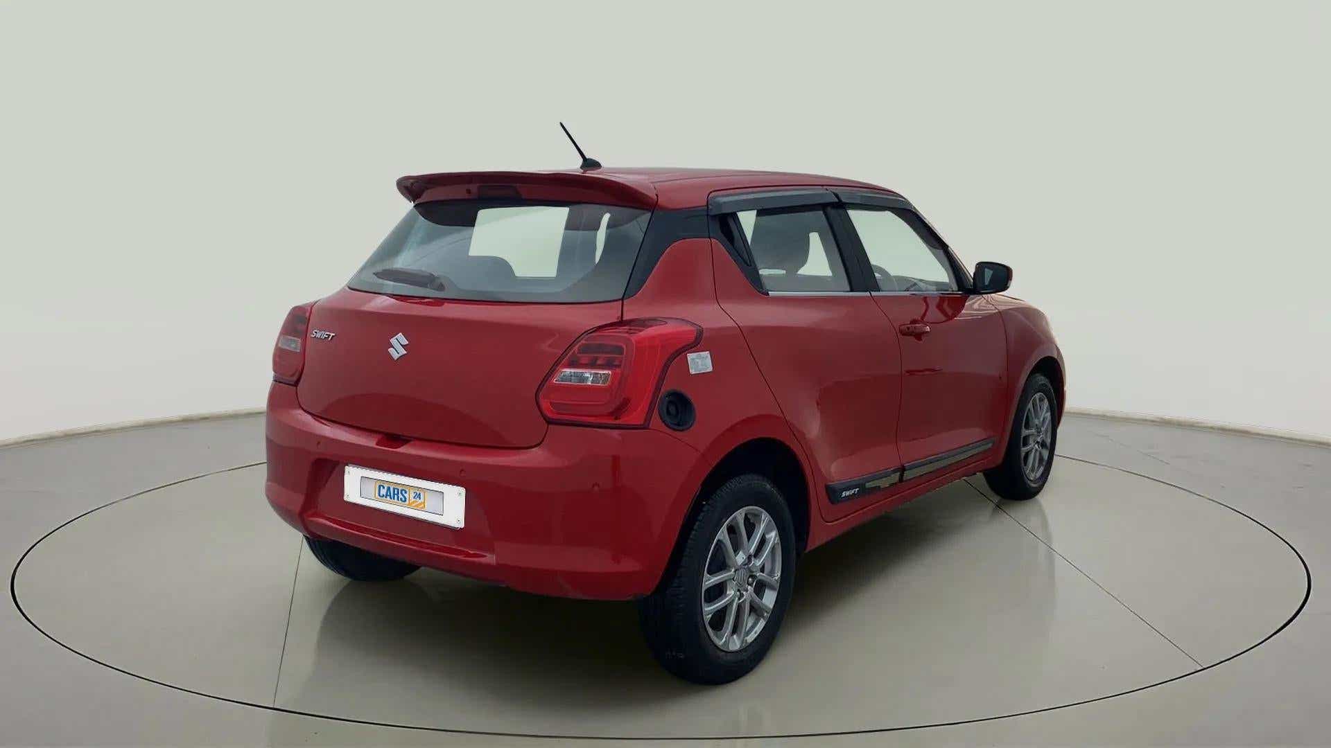 Rear three-quarter view of a solid fire red Maruti Suzuki Swift 2021 - 2023