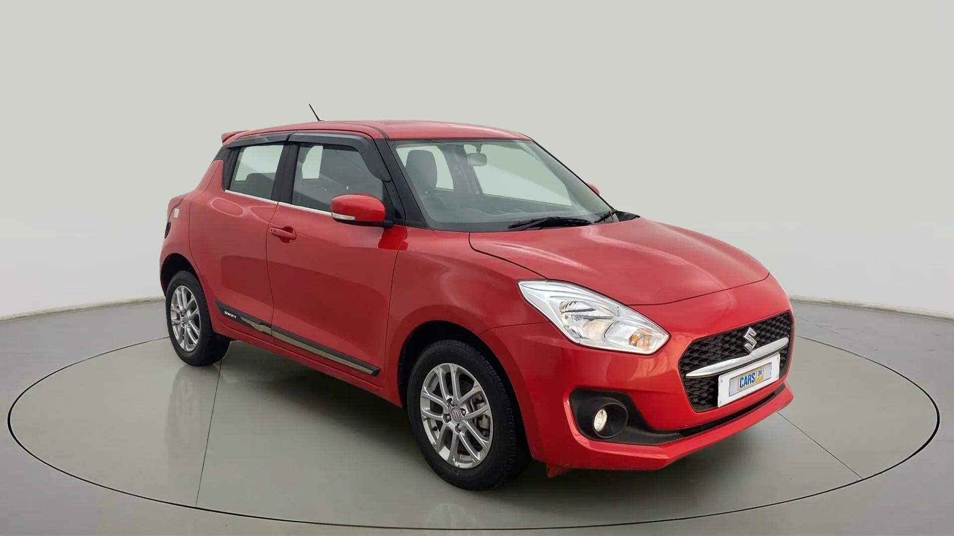 Front three-quarter view of a solid fire red with pearl midnight black roof Maruti Suzuki Swift 2021 - 2023